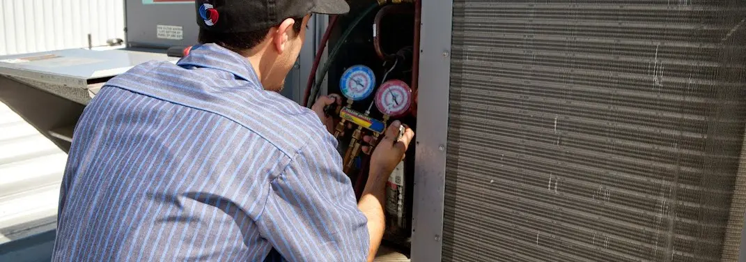HVAC technician servicing a condenser unit in Booneville