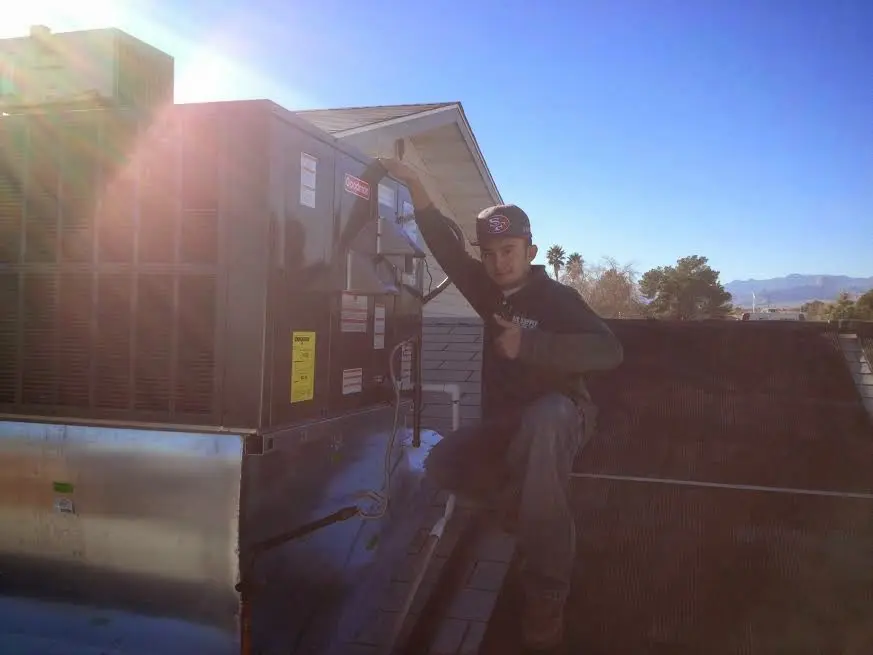 HVAC technician performing Heat Pump Repair on a rooftop unit in Booneville
